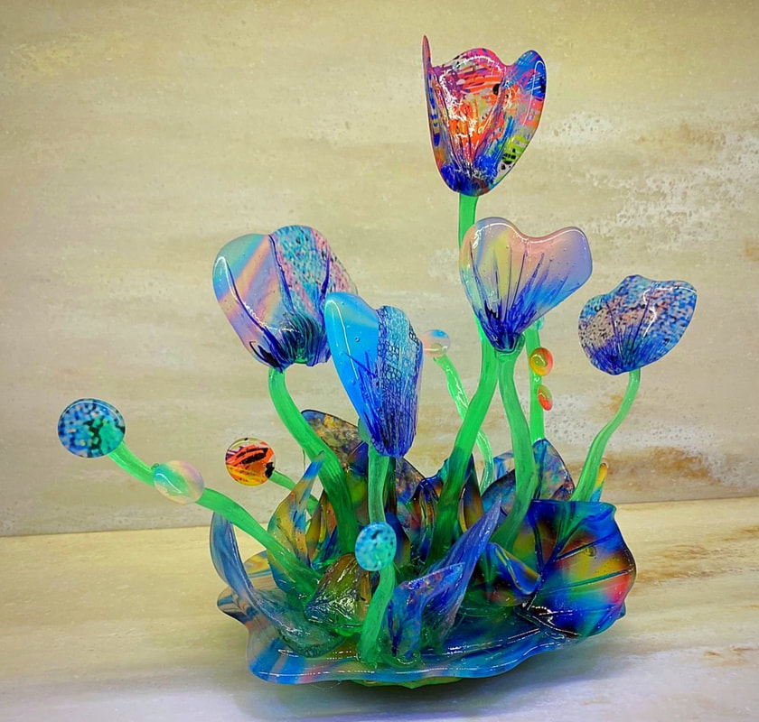 A colorful sugar sculpture of tulips featuring vibrant blue, green, and rainbow hues, with intricate details and a glossy finish.