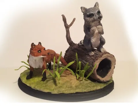 Hand-painted mini diorama of a red fox and raccoon beside a hollow log.