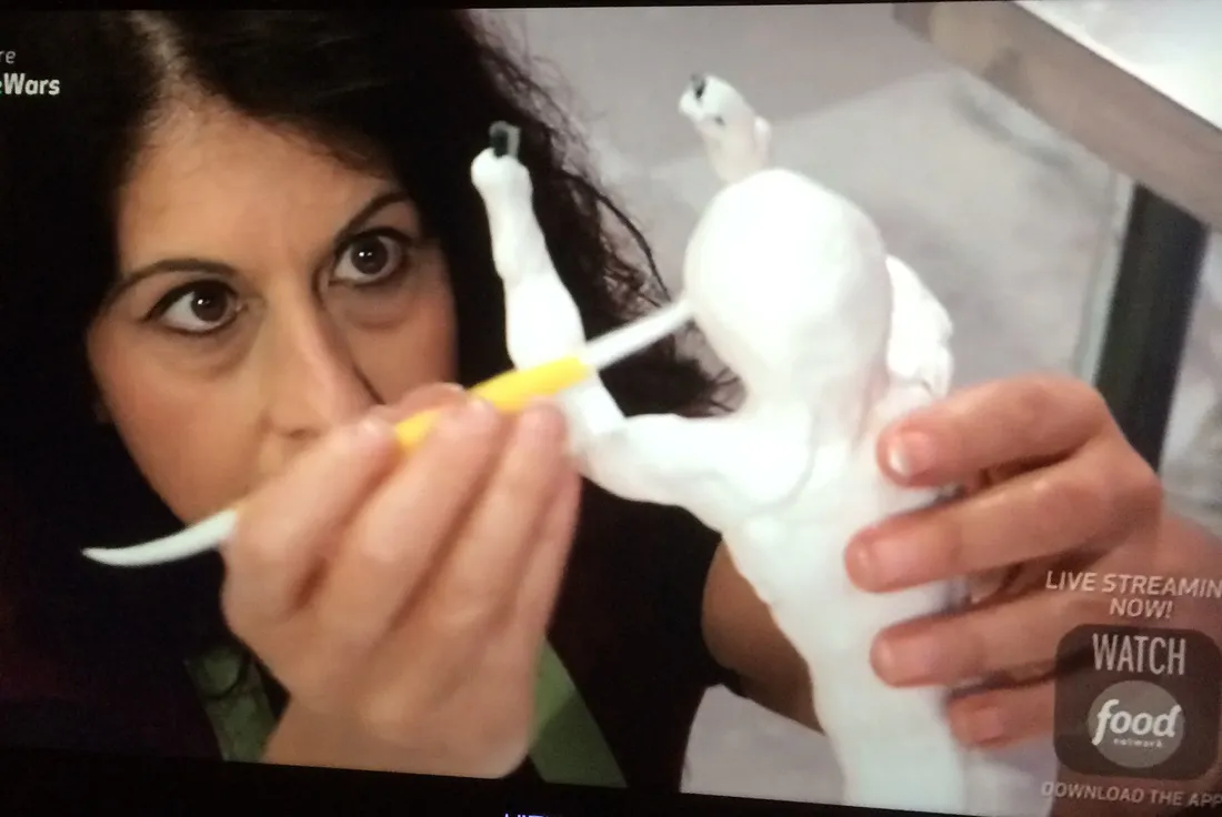 Kim Simons adjusting a cake figurine on Cake Wars.