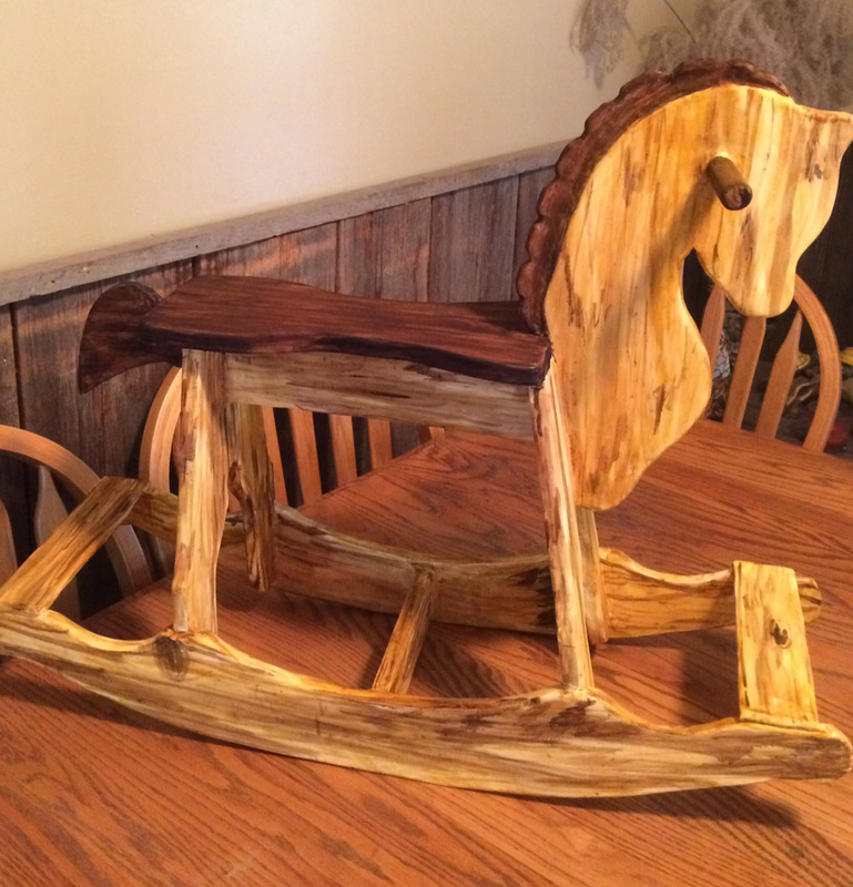 A sculpted sugar rustic wooden rocking horse with a live-edge seat and natural wood grain sits on a dining table.