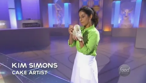 Kim Simons holding a textured cake on the set of Food Network's Sugar Dome.