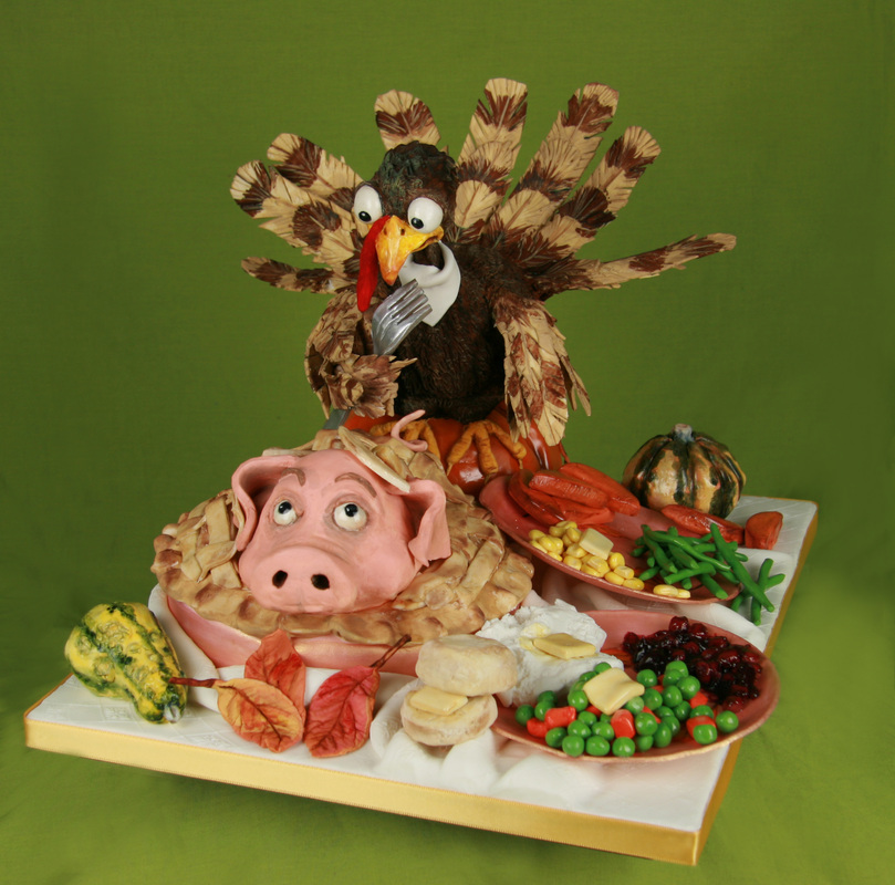 A whimsical cake display features a sculpted turkey holding a fork above a pig-shaped pie and various miniature food items, all set against a solid green background.