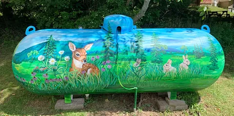 Propane tank painted with a mural of a fawn and rabbits in a meadow.