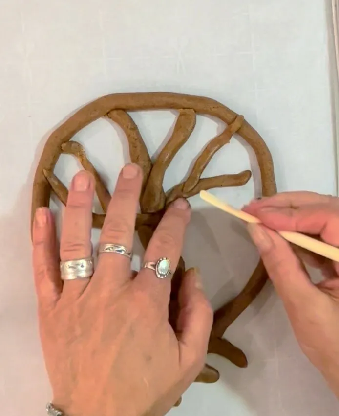 Adding gingerbread dough branches to the tree frame.