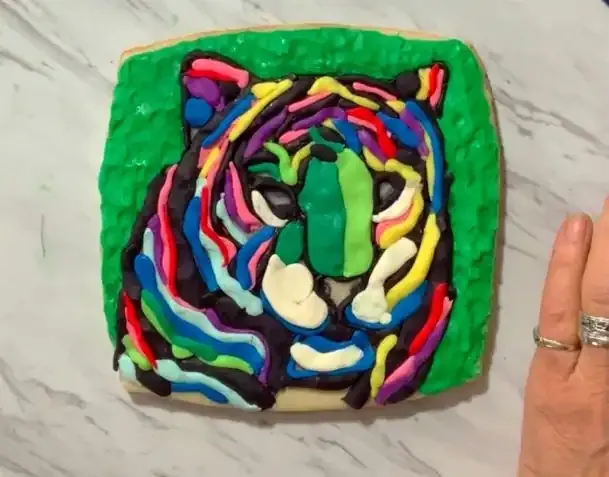 Tiger face built with colorful modeling chocolate stripes on a cookie.