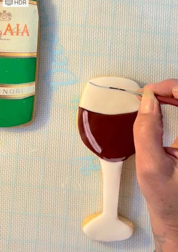 Hand adding petal dust details to the wine glass and bottle cookies.