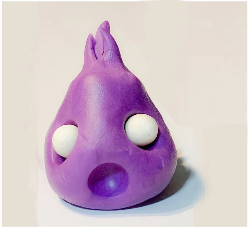 White gumpaste eyes added to purple modeling chocolate lovebird head.