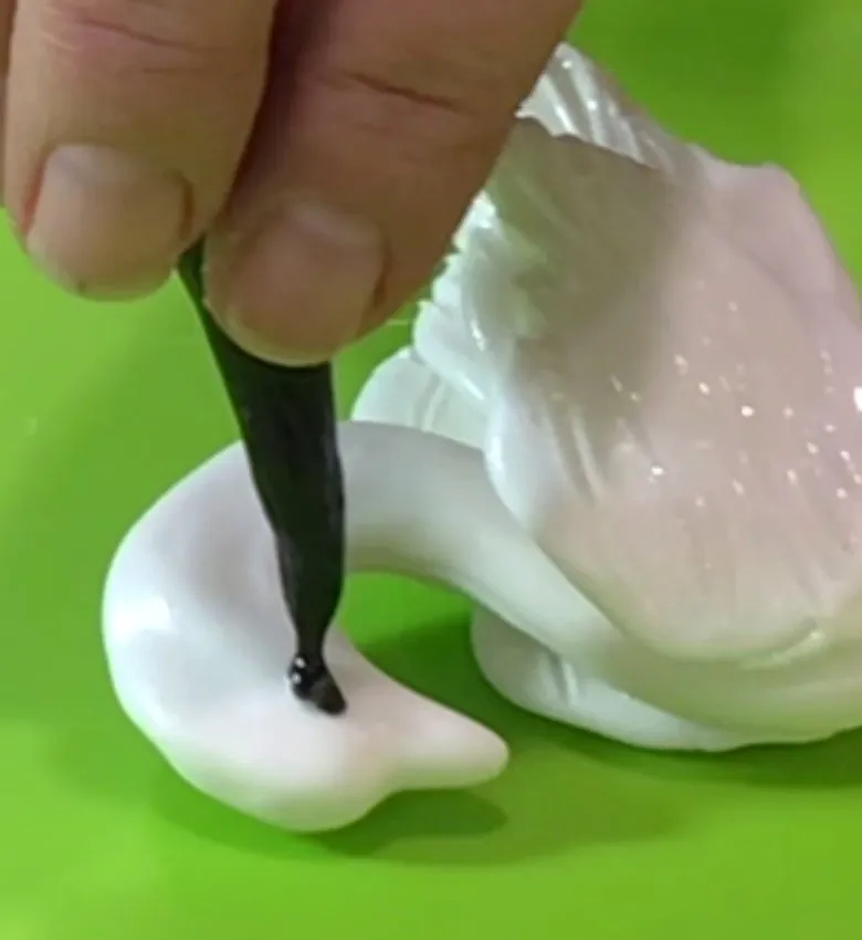 Applying black isomalt to create the swan's eye.