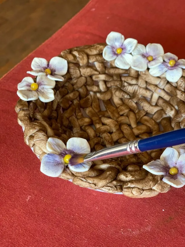 Adding white flowers to the painted chocolate basket