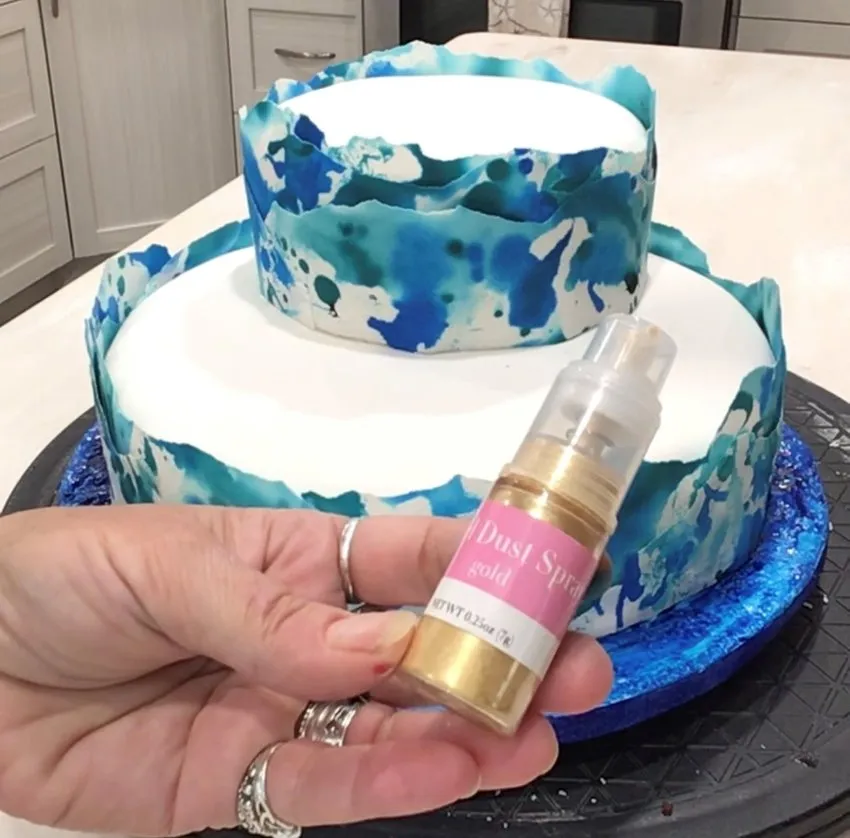 Spraying gold luster dust onto the cake.