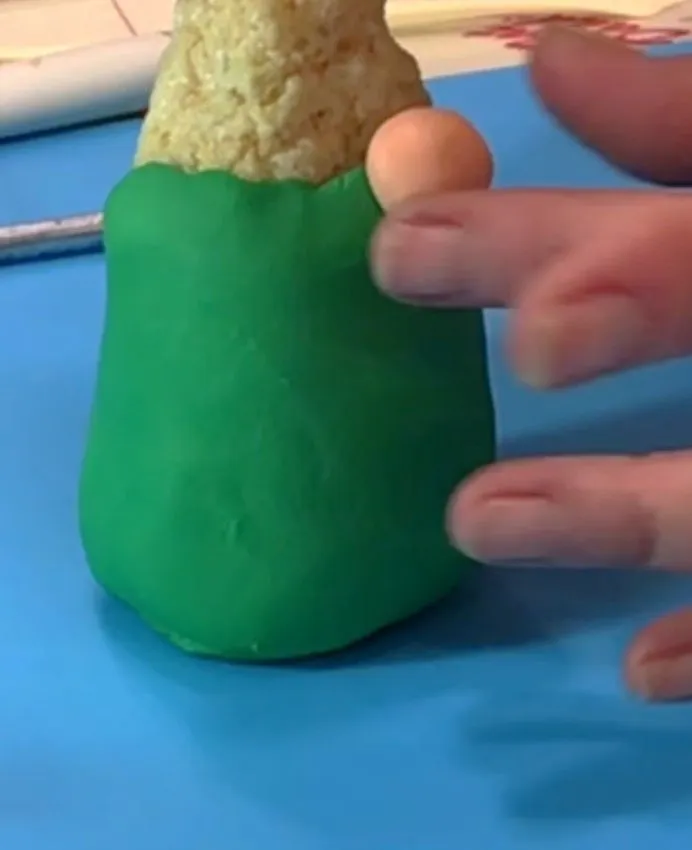 A hand attaches a round fondant nose to the gnome face.