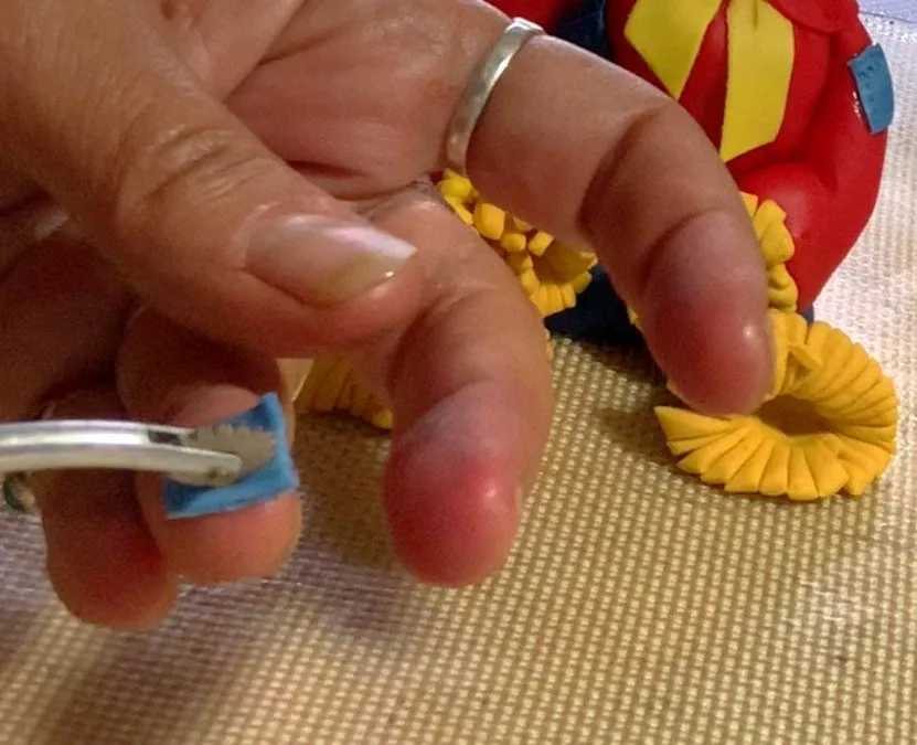 Adding small fondant patches to the scarecrow's jacket.