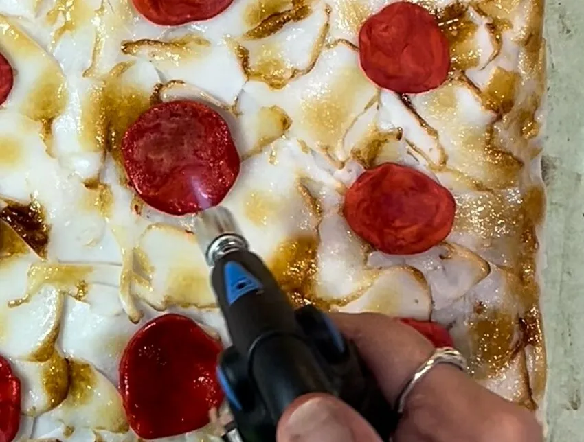 Browning the fondant pizza toppings with a blowtorch.