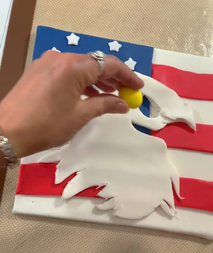 Yellow fondant eye being attached to the eagle head.