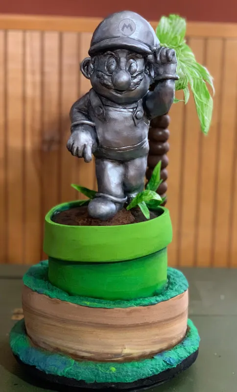 Silver Mario figure in a green pipe planter on a tiered cake base.