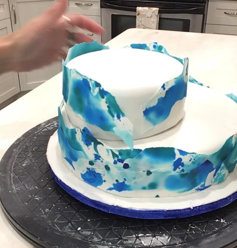 Applying colored paper strips to the top cake tier.