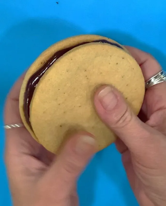 Pressing the top and bottom cookies together.