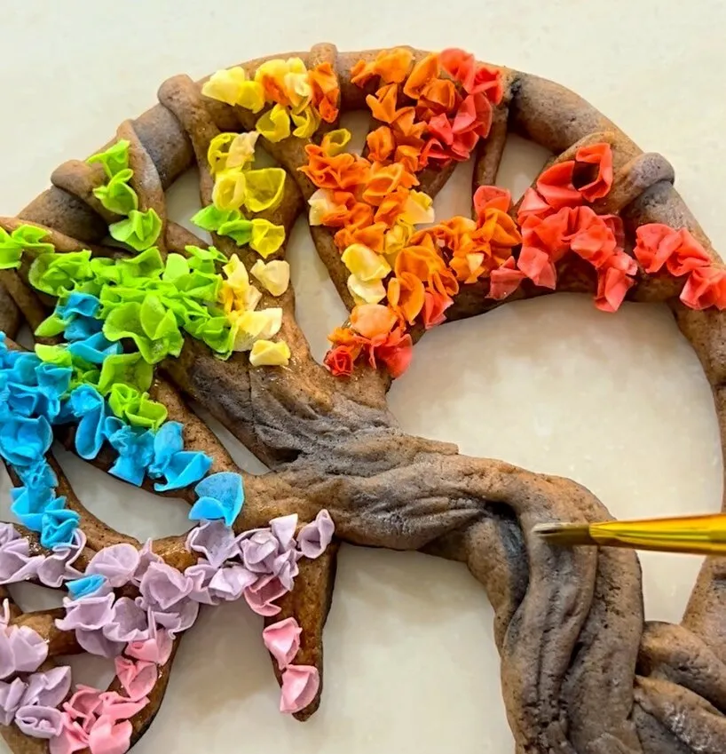 Adding wafer paper flowers to the tree and dusting with petal dust.