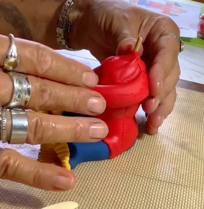 Attaching the fondant arms to the scarecrow's body.