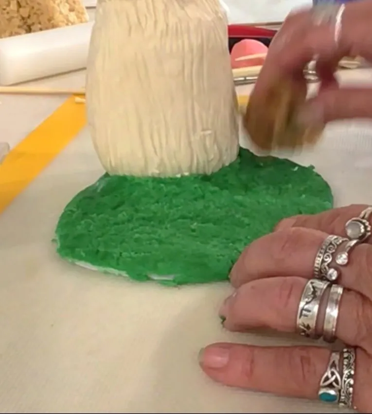 Hand brushing the bunny body attached to a green fondant base.