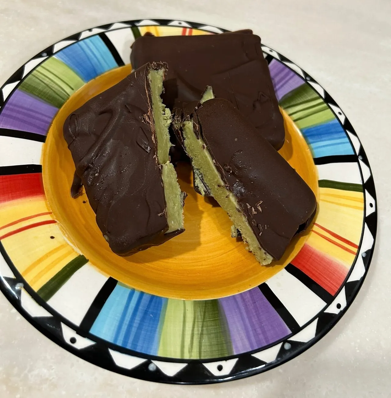 Two green avocado-banana frozen treats on sticks arranged on a plate with one split in half