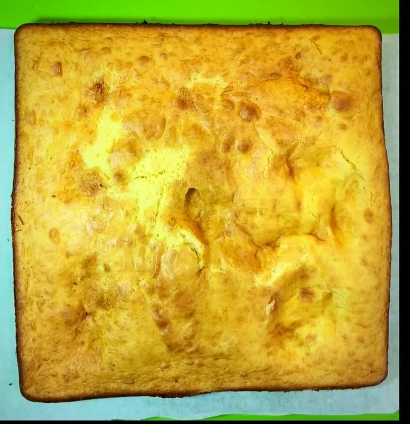 A square baked cake on parchment paper.