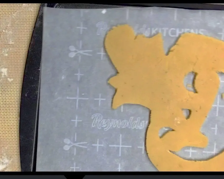 Baked Halloween cookie shapes cooling on a silicone baking mat.