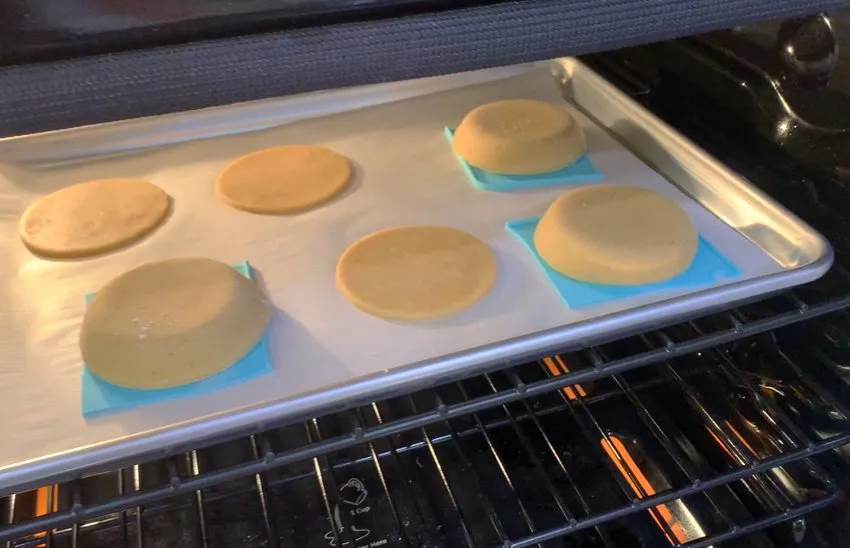 Sugar cookies baking on a sheet pan in the oven.