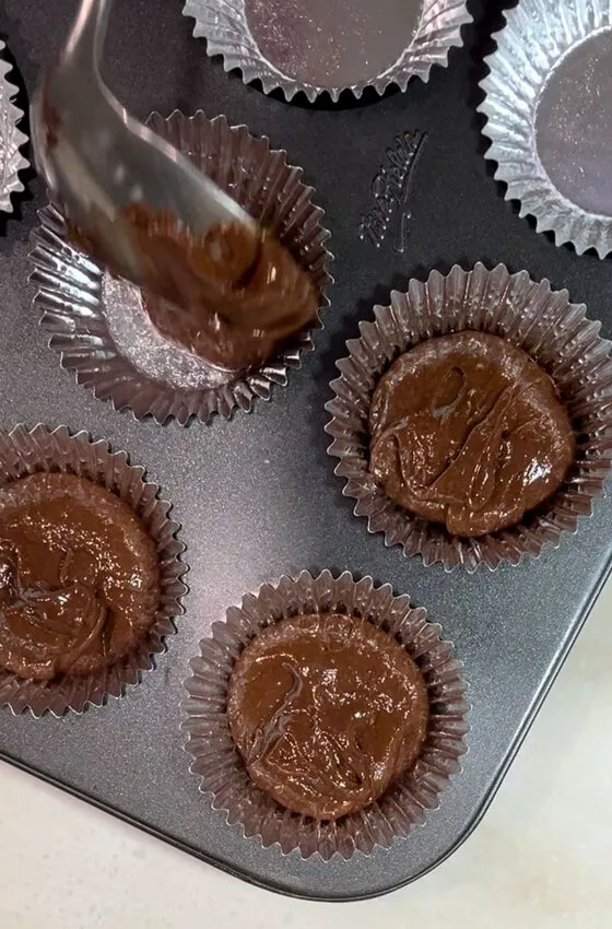 Batter being spooned into cupcake liners