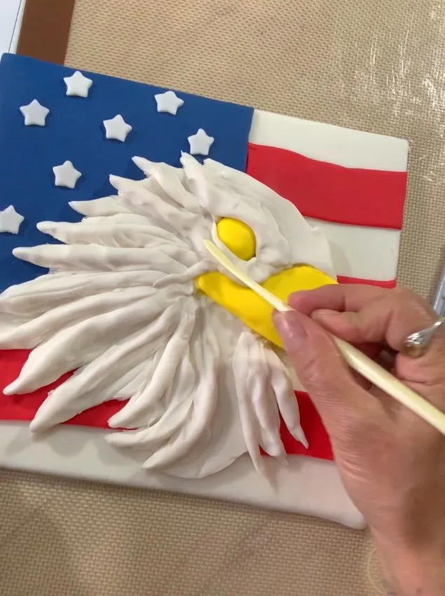 Hand blending fondant with a clay tool on the eagle head.