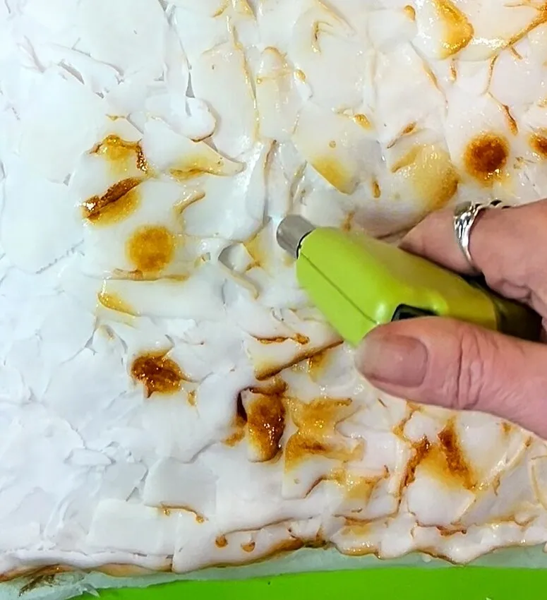 Using a blowtorch to brown the fondant for a baked crust effect.