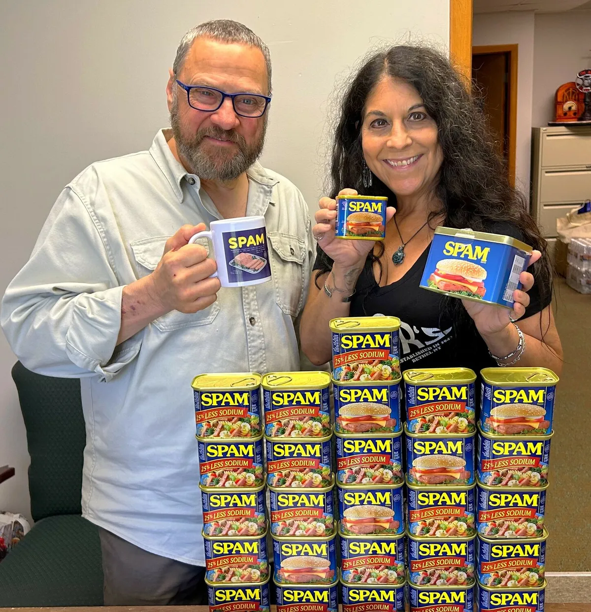 Kim Simons and Paul Ciliberto holding SPAM cans in an office.