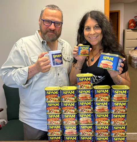 Kim Simons and Paul Ciliberto holding SPAM cans in an office.