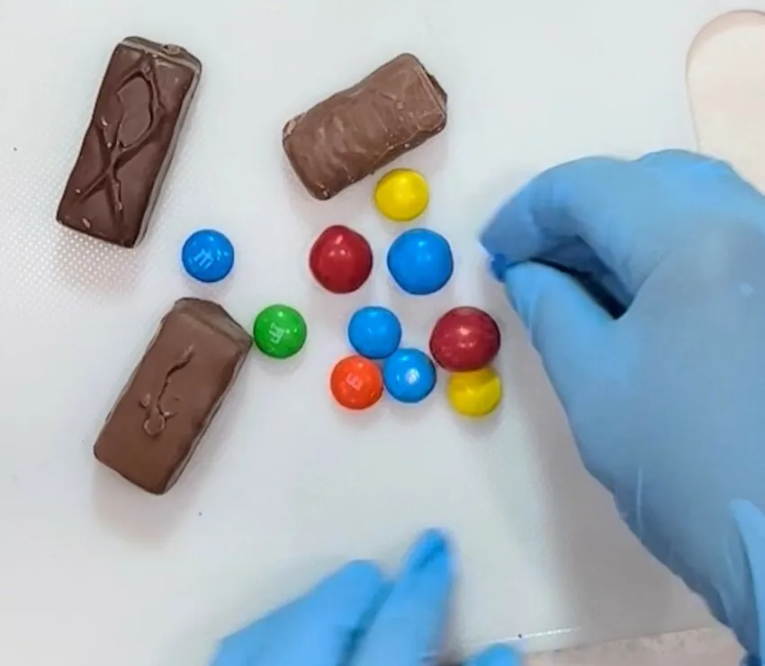 Chocolate bars and M&Ms candies on a white surface