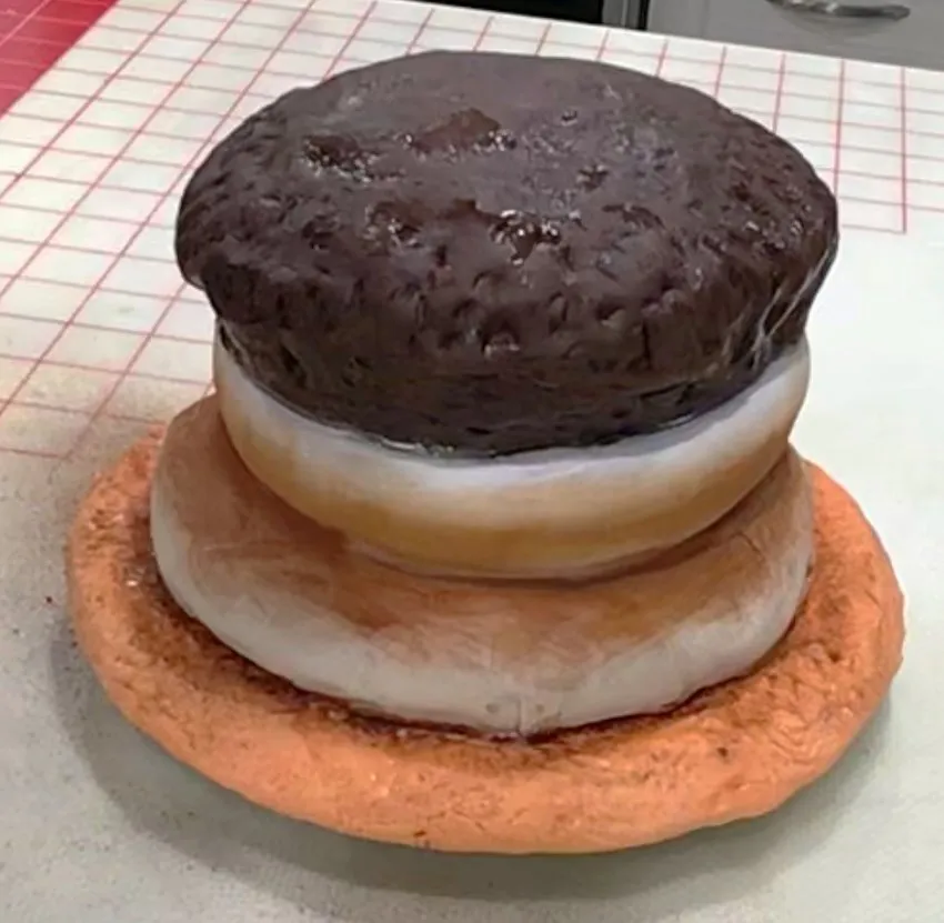 A hand brushes edible color onto the fondant bottom bun layer.