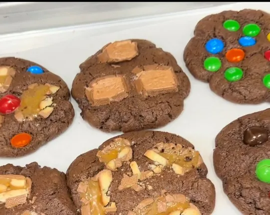 Baked cookies with colorful candy toppings cooling on a white surface