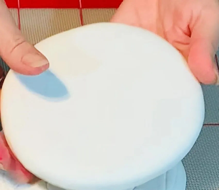 Covering a round sugar cookie with white fondant.