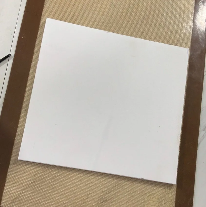 White fondant covering a cake or cookie base on a work mat.
