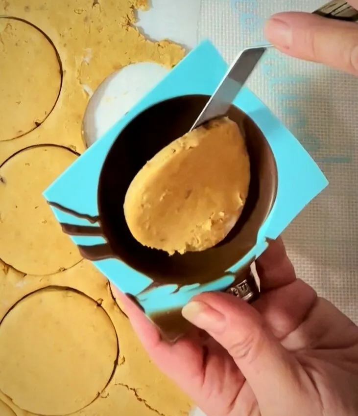 Cutting peanut butter filling with a cookie cutter.