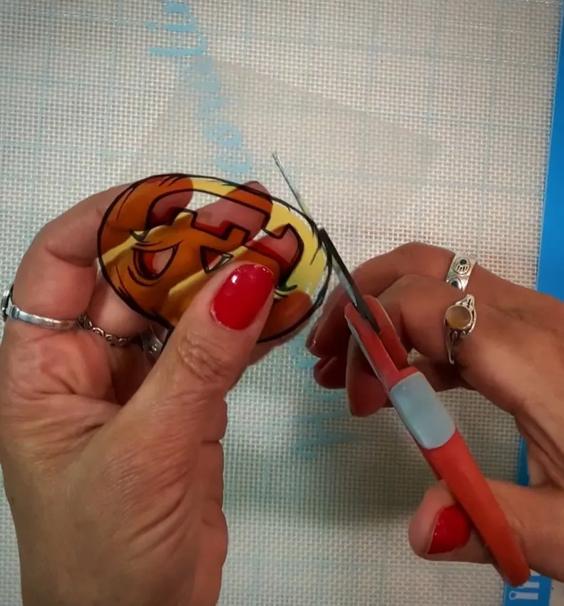 Hands cut out Halloween images from printed cello sheets with scissors.