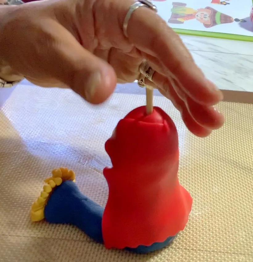 Cutting the red fondant jacket shape with a wheel cutter.