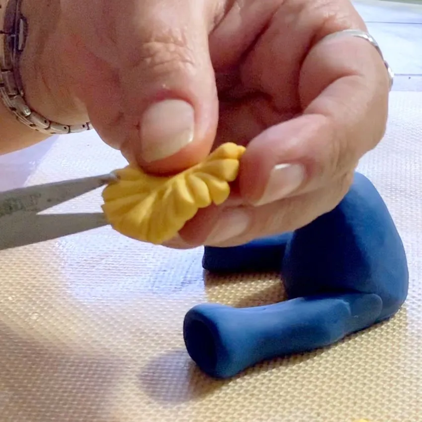 Cutting yellow fondant fringe with scissors for the straw.