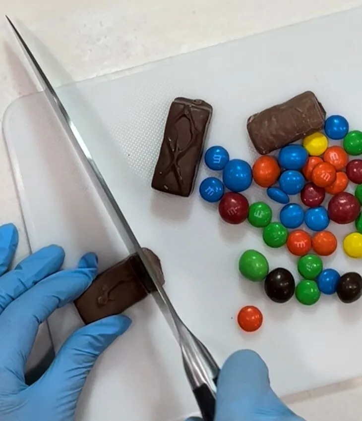 Hand slicing a chocolate bar on a cutting board