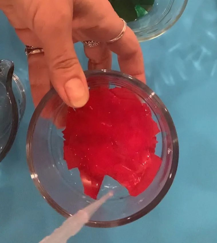 Adding water to dissolved edible fabric sheet mixture in a bowl.