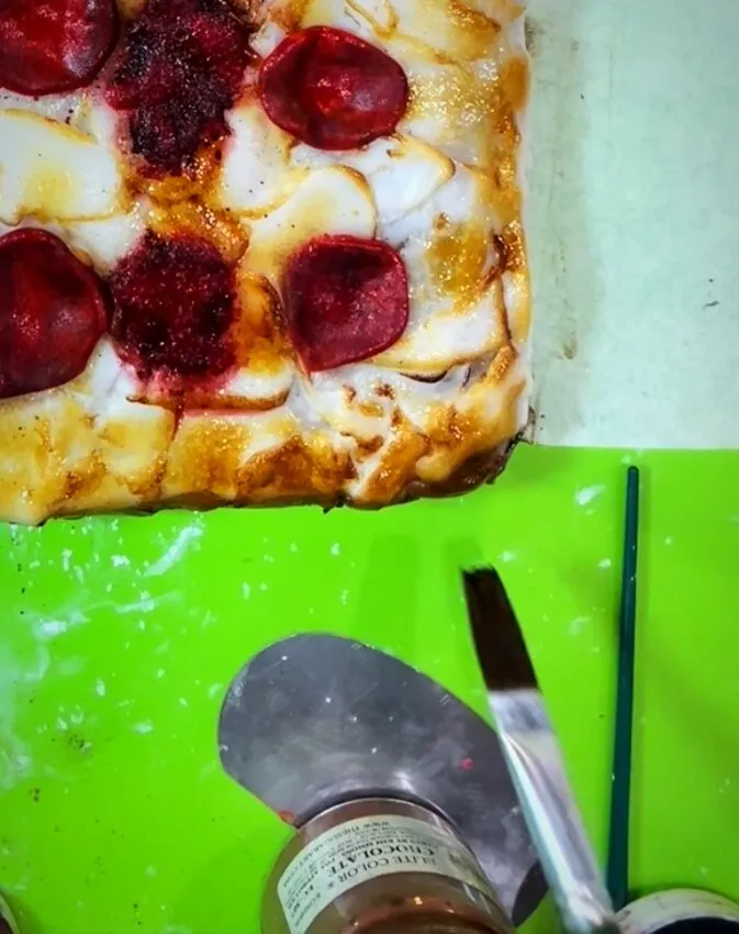 Dusting the pizza cake edges with edible paints.