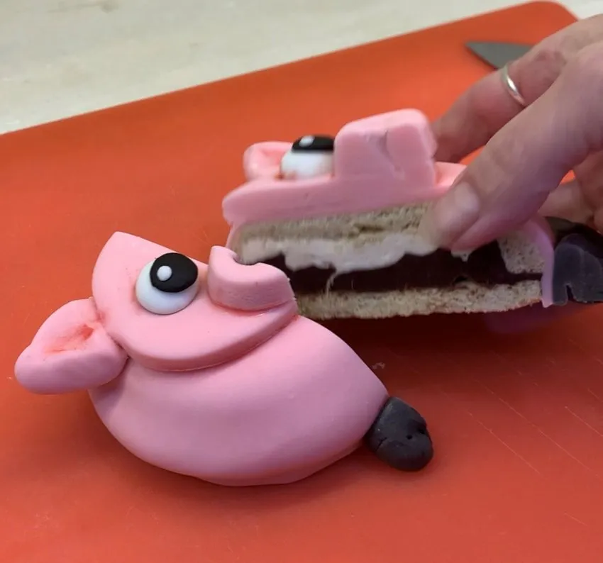 Lifting the top half of the pig cookie to reveal the layered interior.