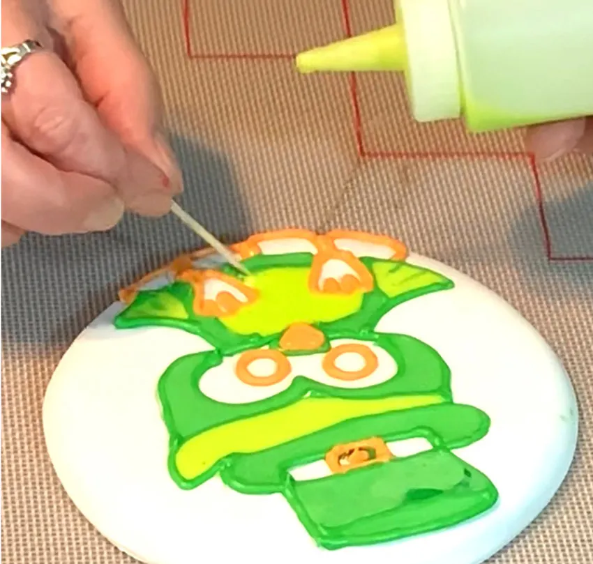 Flooding colors onto the owl design with a toothpick.