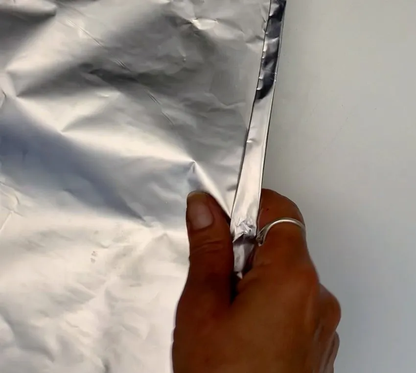 Hand holding a sheet of aluminum foil