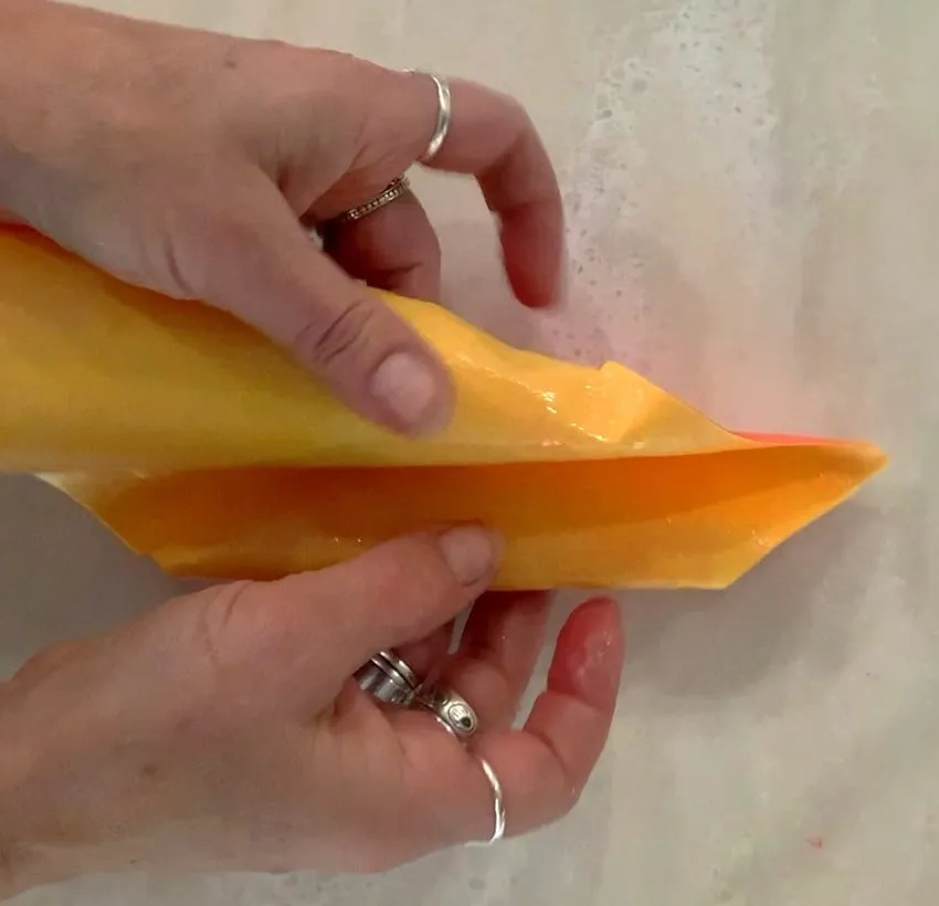 Hands folding a wet wafer paper petal into shape over a sink.