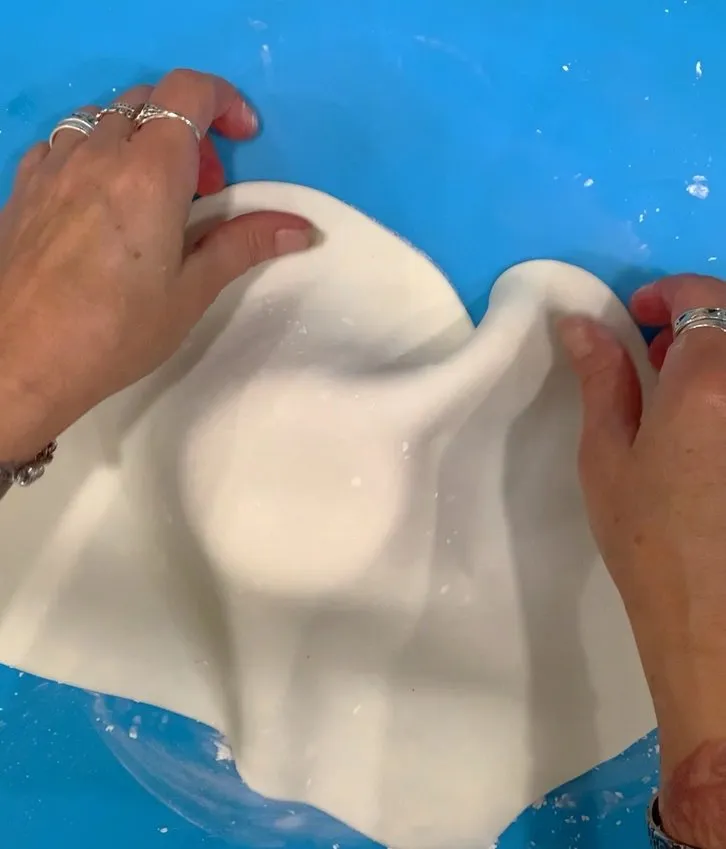 Stretching white fondant to cover the cookie body.